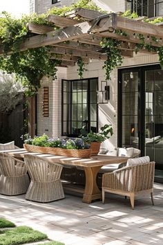 an outdoor dining area with wicker chairs and table surrounded by greenery on the patio