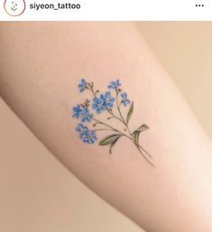 a small blue flower tattoo on the arm