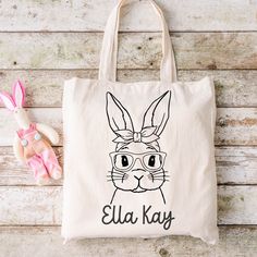 "Easter is on its way! A fun alternative to the traditional Easter basket are these adorable, personalized canvas totes. Perfectly sized for your littles one - not too big or bulky, but roomy enough for plenty of eggs and goodies!  * Sublimated in-house in our shop in Louisiana * Cotton/linen tote bag * Enter personalization in provided space * 12\" wide X 14\" tall * Ready to ship or pickup in 1-2 business days" Cute Rectangular Canvas Bag For School, Playful Bag Gift For Back To School, Playful Bags For Back To School Gift, Playful Everyday Bags For Back To School, Fun Rectangular Bags For Gifts, Cute Letter Print Canvas Bag For School, Cute Canvas Bag With Letter Print For School, Fun Tote Bags For School, Fun Rectangular Bags Ideal For Gifts