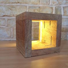 a small wooden box with a light in it on a table next to a brick wall