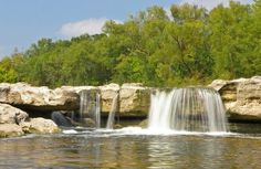 there is a small waterfall in the middle of the water with rocks on both sides