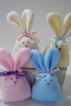 four stuffed animals sitting next to each other on a white surface with one bunny in the middle