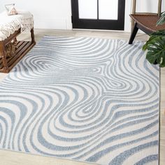 a white and blue area rug with waves on it in front of a chair next to a window