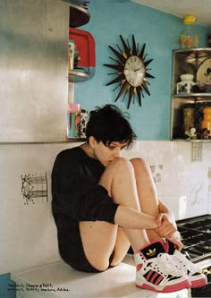 a young man sitting on the kitchen counter with his feet up in front of him