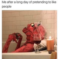 a bathtub filled with red stuff next to a glass of wine and a toothbrush