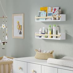 a baby's nursery room with white furniture and shelves on the wall, including a crib