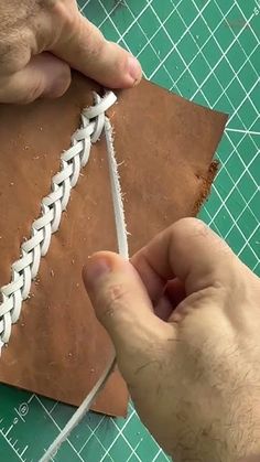 someone is making a leather book cover with braiding