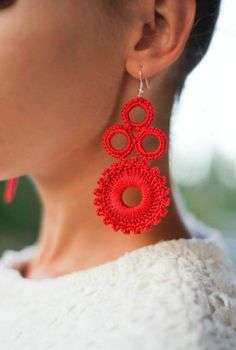 a woman wearing red earrings with circular design