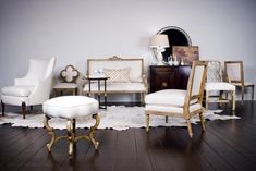 a living room filled with white furniture and wooden floors