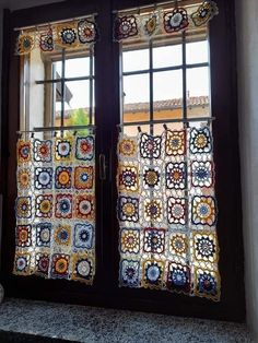 two windows with crocheted curtains on them in front of a window sill