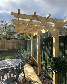 an outdoor dining table and chairs under a pergolated arbor in the back yard