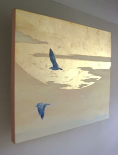 two blue birds flying in the sky on a white wall next to a window with sunlight coming through it