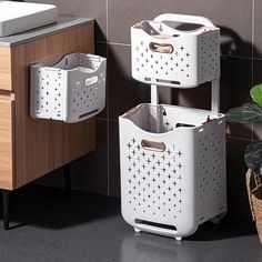 two white baskets sitting next to each other on a tiled floor in front of a sink