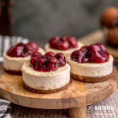 mini cheesecakes topped with cherries on a wooden platter, ready to be eaten