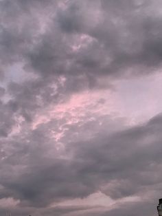 an airplane is flying high in the sky with dark clouds above it and buildings below