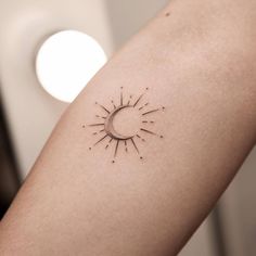 a woman's arm with a small sun tattoo on the back of her left arm