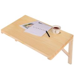 a small wooden table with a cup of coffee on it and a notepad next to it