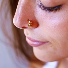 a close up of a woman's nose with a tiny gold leaf on it