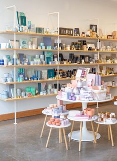 the inside of a store with shelves full of products and candles on tables in front of them