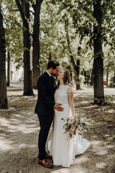 a bride and groom kissing in the woods