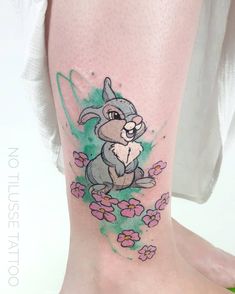 a tattoo on the leg of a woman with an image of a rabbit and flowers