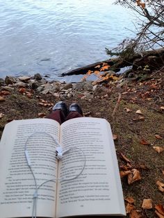 an open book sitting on the ground next to a body of water