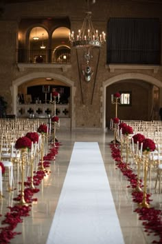 the aisle is lined with white chairs and red rose petals on each chair, along with candles