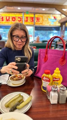 a woman sitting at a table looking at her cell phone