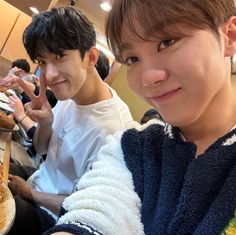 two young men sitting next to each other at a table with food in front of them