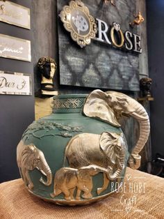 an elephant and baby elephant painted on a green vase in front of a sign that says rose