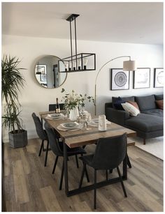 a dining room table and chairs in front of a couch with pictures on the wall