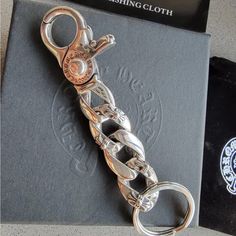 a pair of scissors sitting on top of a black book next to a metal chain