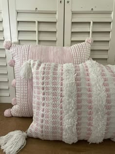 two pink and white pillows with tassels on them