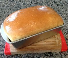 a loaf of bread sitting on top of a cutting board next to a red spatula