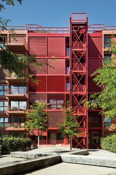 a red building with stairs leading up to it's second story and trees in the foreground