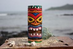 a colorful vase sitting on top of a wooden table next to the ocean