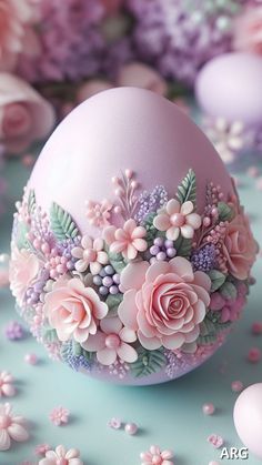 an egg decorated with flowers and leaves on a blue surface surrounded by other eggs in pastel colors