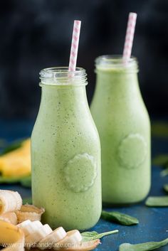 two glasses filled with green smoothie next to bananas