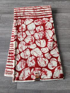 a red and white scarf on top of a wooden floor