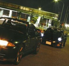 two cars parked in front of a building at night