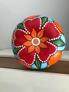 an orange and blue painted rock with flowers on it