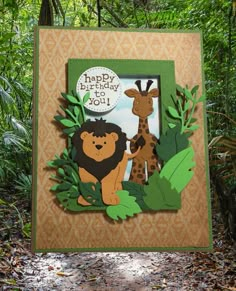 a birthday card with an animal and giraffes on the front, surrounded by leaves