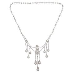 A Marcus natural pearl, diamond and platinum pendant necklace. The central pendant has a diamond motif, with three diamonds in a lozenge, atop a five row splash of pavé set diamonds, topped with a pearl, with three diamond capped pearl drops, suspended from diamond set chain links. Either side of the centre pendant is a pearl, connected by diamond chain links, with a swag of rub over set diamond chain links below, suspending three graduating rows of diamond chain links, terminating with diamond capped pearl drops, onto a chain of natural pearls, on platinum wired links, signed, on the back, with M.&CO. in a cartouche, set with Edwardian-cut and eight-cut diamonds, mounted in platinum, on a jump and bolt ring clasp, circa 1920. With a scratched inventory number D2453, accompanied by GIA rep Art Deco White Gold Necklace With Rose Cut Diamonds, Formal Drop Pearl Necklace In White Gold, Formal Drop White Gold Pearl Necklace, Formal Drop-shaped White Gold Pearl Necklace, Classic Platinum Necklace With Rose Cut Diamonds, Elegant Necklace With Rose Cut Diamonds In Platinum, Elegant Platinum Necklace With Rose Cut Diamonds, Platinum Pendant Necklace With Rose Cut Diamonds, Formal Platinum Necklace With Rose Cut Diamonds