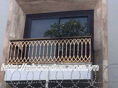 an iron balcony railing on the side of a building with barbed wire around it and a tree in the window