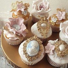 cupcakes decorated with pink and white flowers on a gold plated platter