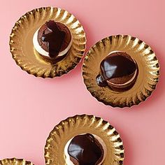 three chocolate covered desserts sitting on top of gold paper plates next to each other