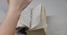 an open book being held up by someone's hand on a table with white speckles