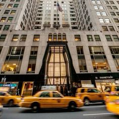 taxi cabs and taxis drive past the entrance to a building in new york city