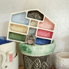 there is a vase with many different colors on it and two mugs next to each other