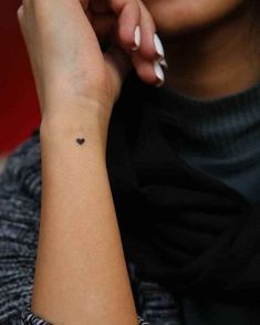 a woman with a small heart tattoo on her wrist